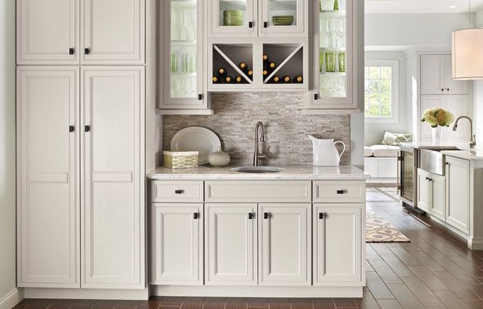 A kitchen with white cabinets , a sink , and a wine rack.