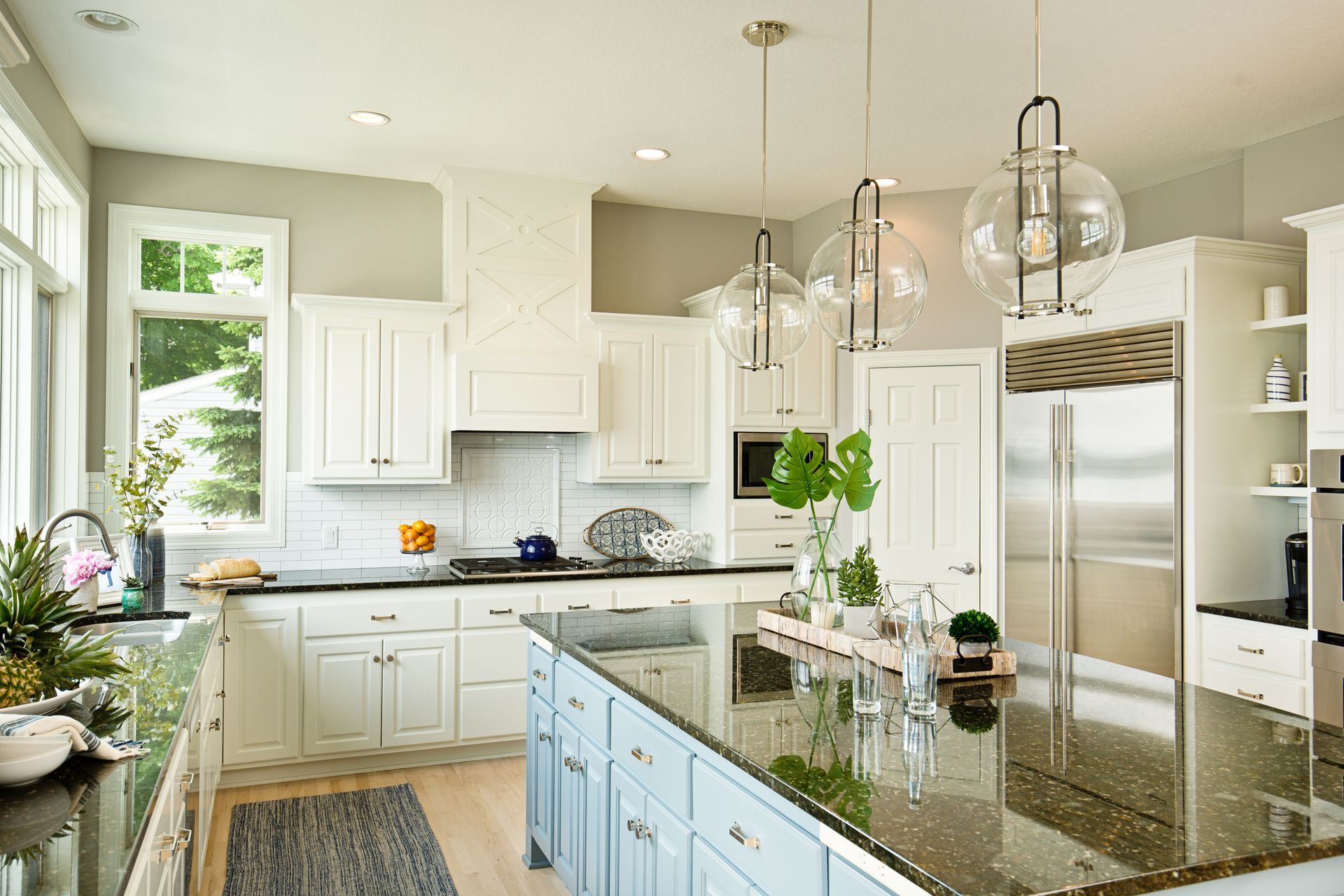 A kitchen with white cabinets , black counter tops , and stainless steel appliances.