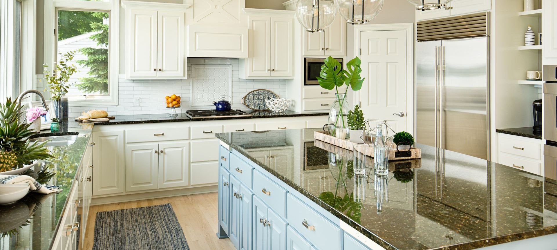 A kitchen with white cabinets , black granite counter tops , and stainless steel appliances.