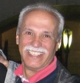 A man with gray hair and a mustache is smiling for the camera.