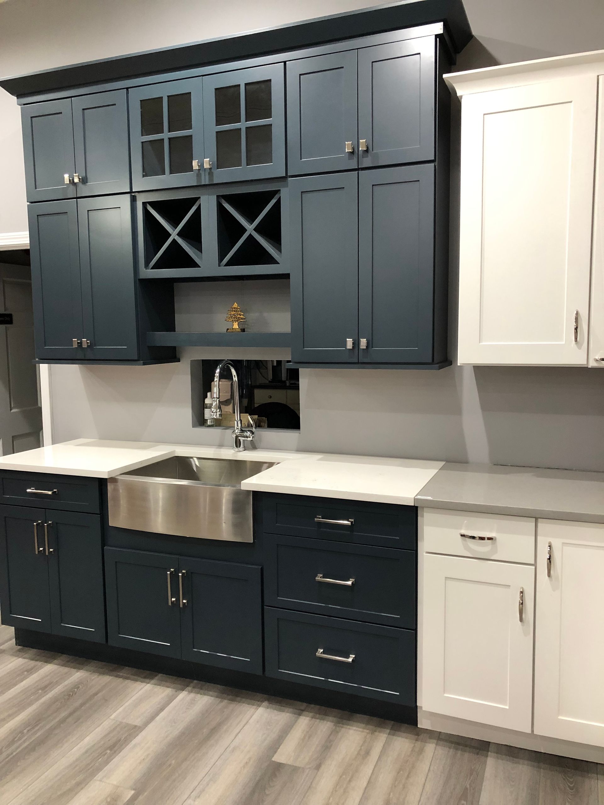 A kitchen with blue cabinets and white cabinets and a stainless steel sink.
