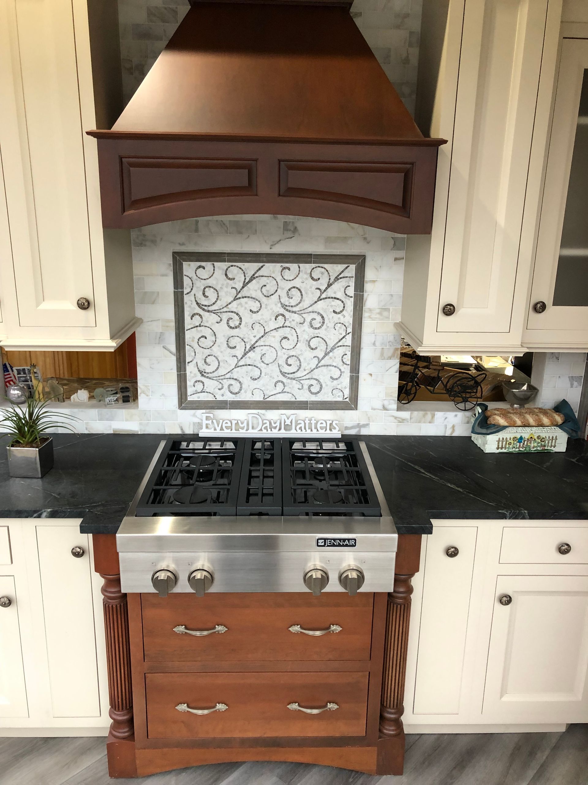 A kitchen with a stove top oven and a hood above it.