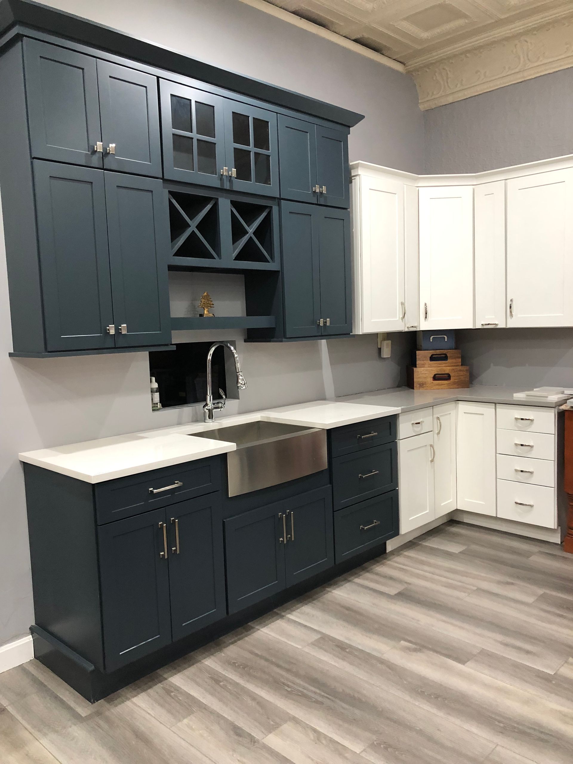 A kitchen with blue cabinets and white counter tops and a sink.