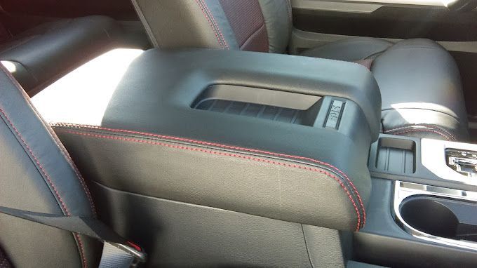 A black car with a red stitching on the arm rest