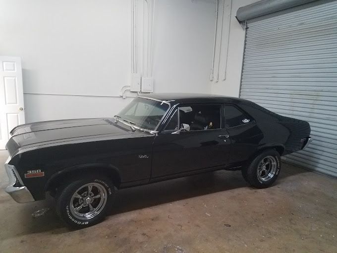 A black car is parked in a garage next to a garage door.