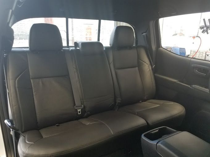 The back seat of a truck with black leather seats.