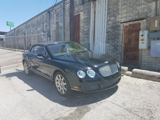A black bentley convertible is parked in front of a building.