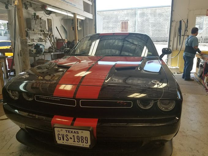 A black and red dodge challenger is parked in a garage.