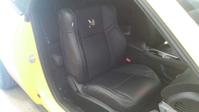 A yellow car with a black seat in the back seat.