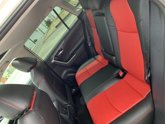 The back seat of a car with red and black seats