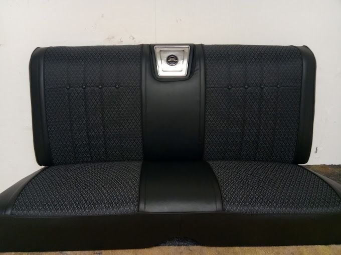 A black car seat with a silver emblem on it
