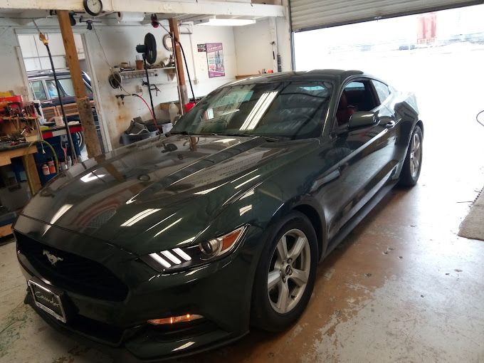 A gray mustang is parked in a garage.