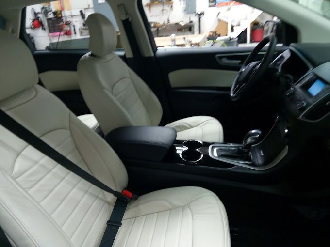 The inside of a car with white seats and a black seat belt