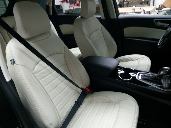 A car with white seats and a black seat belt