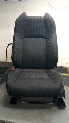A black car seat is sitting on top of a concrete floor.