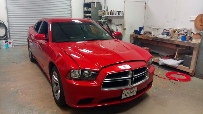 A red dodge charger is parked in a garage