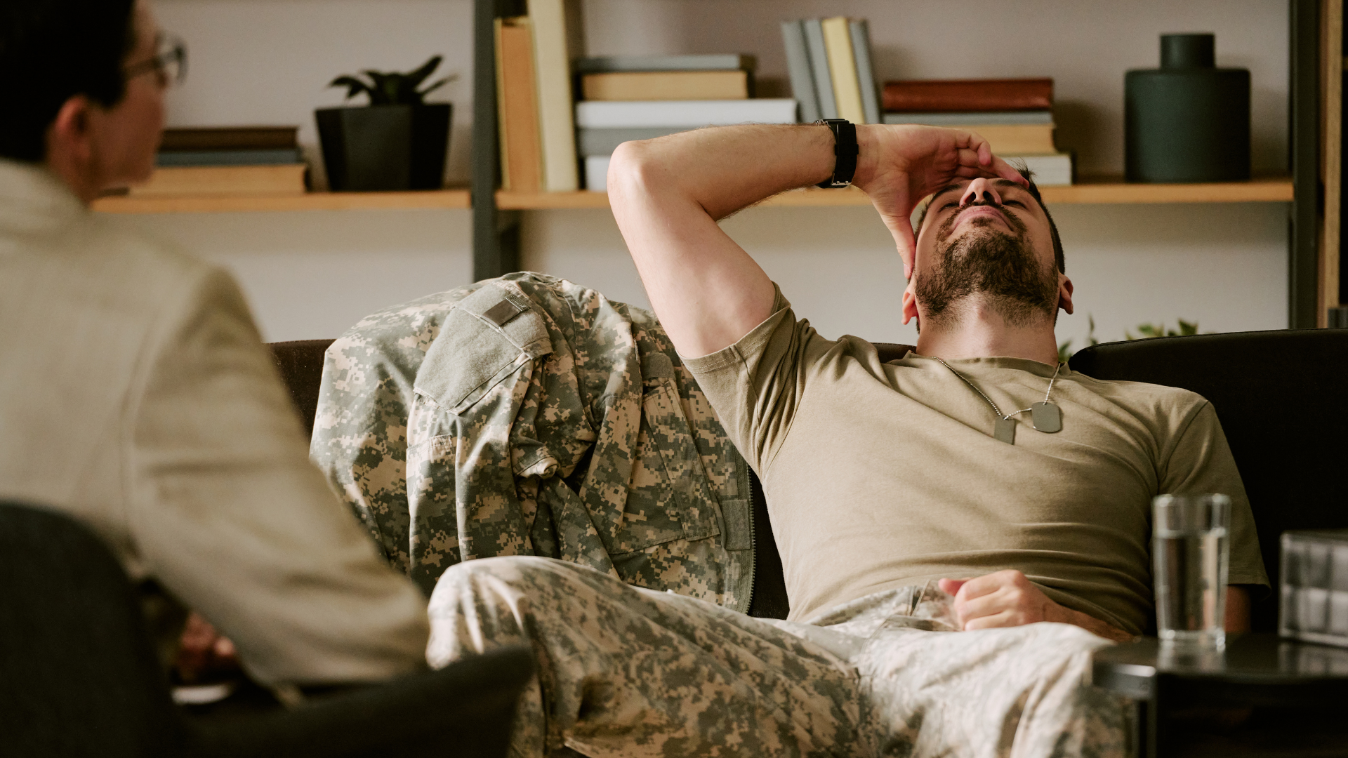 Man reclining on a couch, stretching with one arm behind his head in a cozy living room
