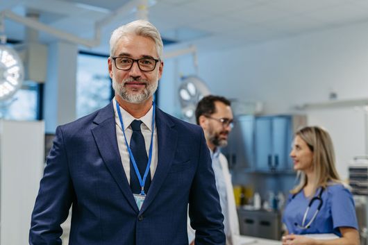 Professional IT consultant smiling confidently, standing in a modern office environment, symbolizing expert guidance and support in technology solutions.