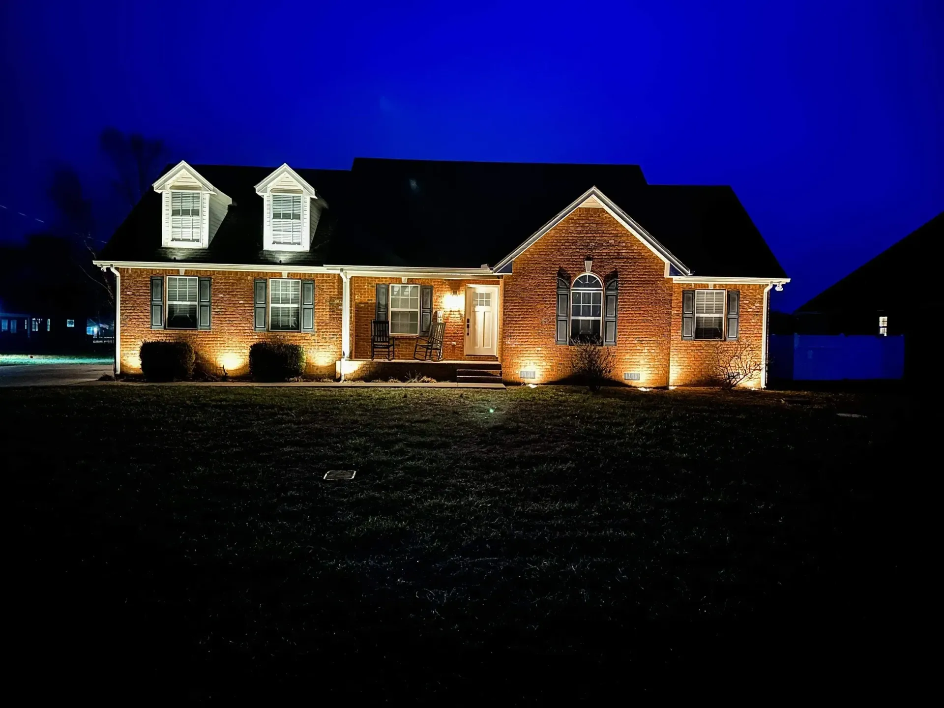A brick house is lit up at night with a blue sky in the background