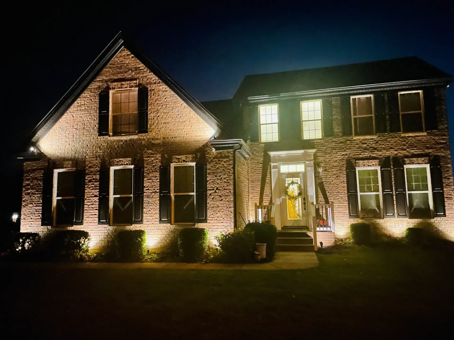 A large brick house is lit up at night.