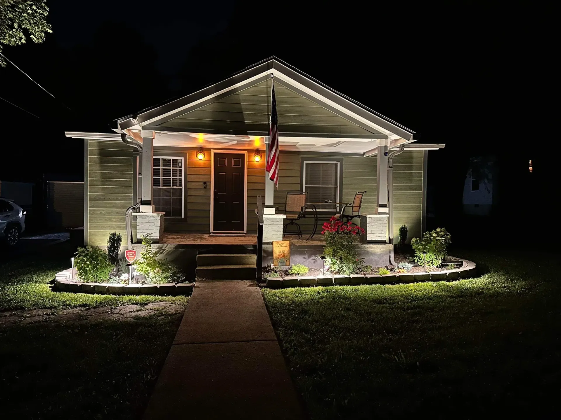 A house is lit up at night with a flag on the porch.