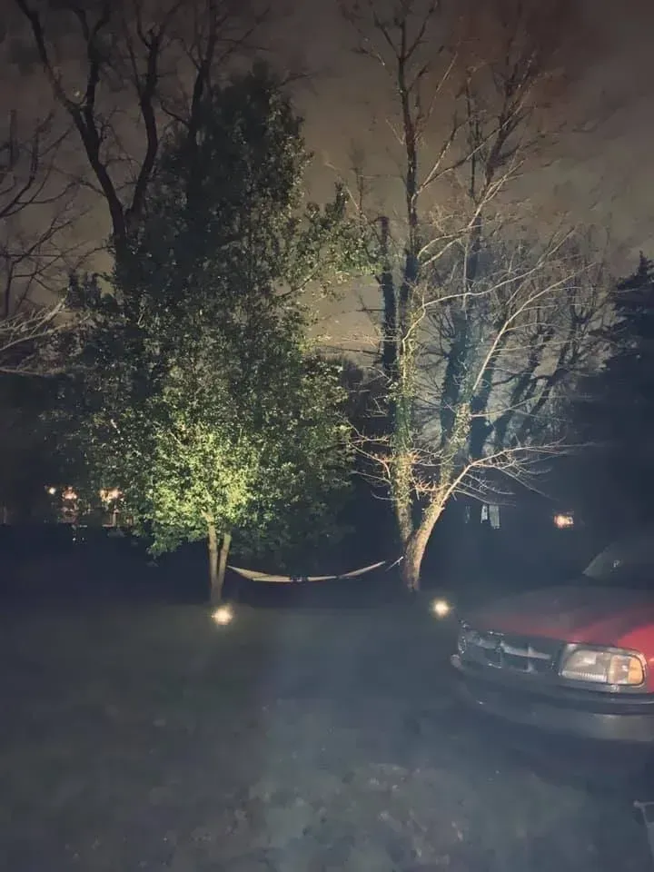 A red truck is parked in a driveway at night.