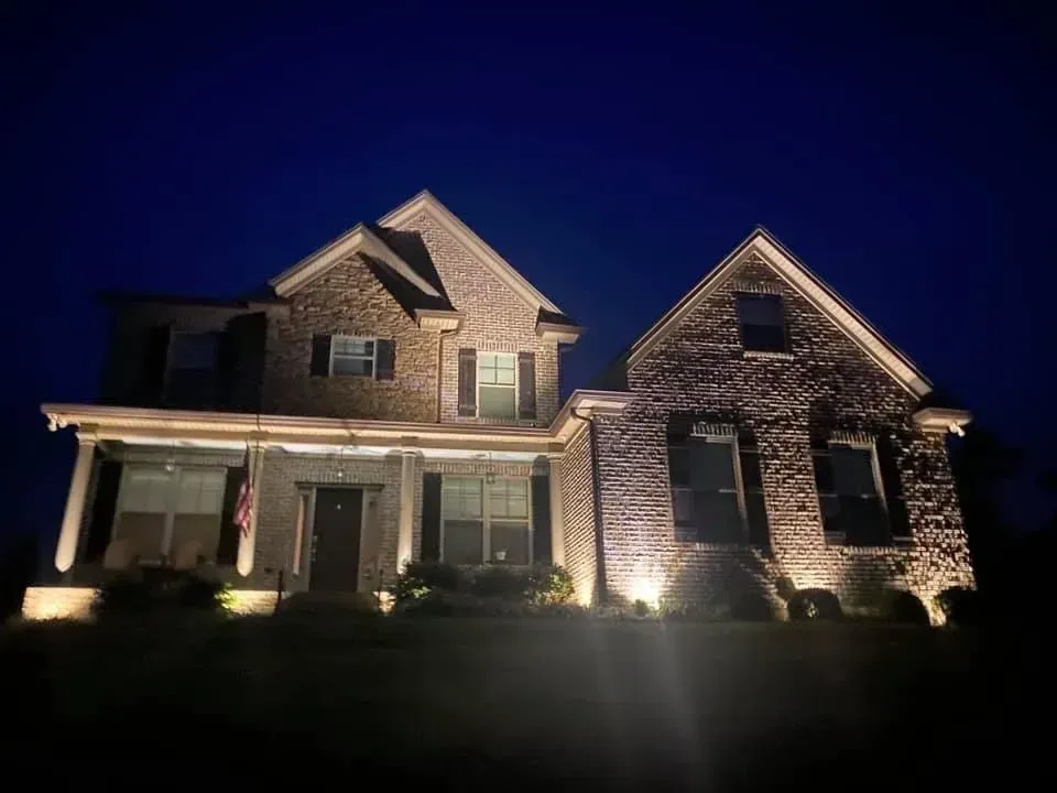 A large brick house is lit up at night.