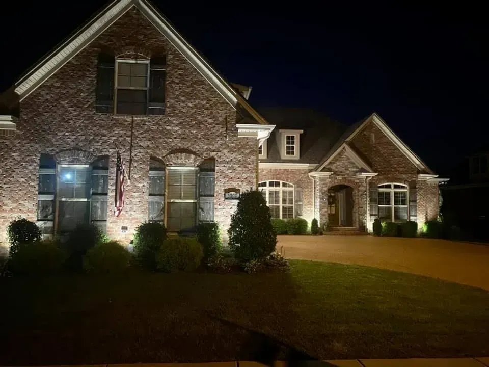 A large brick house is lit up at night