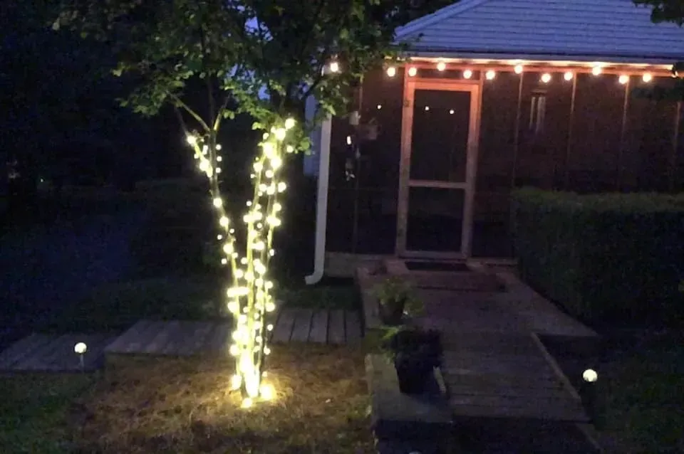 A house with a screened in porch and a tree with lights on it