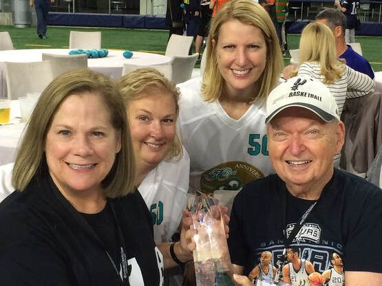 A group of people posing for a picture with one man wearing a spurs shirt