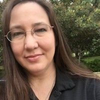 A woman wearing glasses and a black shirt is smiling for the camera.