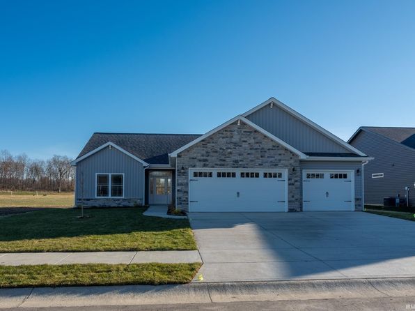 Gray and stone-faced ranch house with a two-car garage under a clear blue sky.