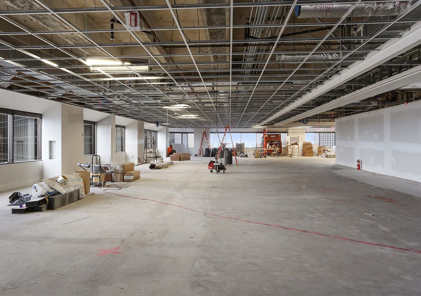 Interior of a building under construction; exposed ceiling grid, drywall, and concrete floor.