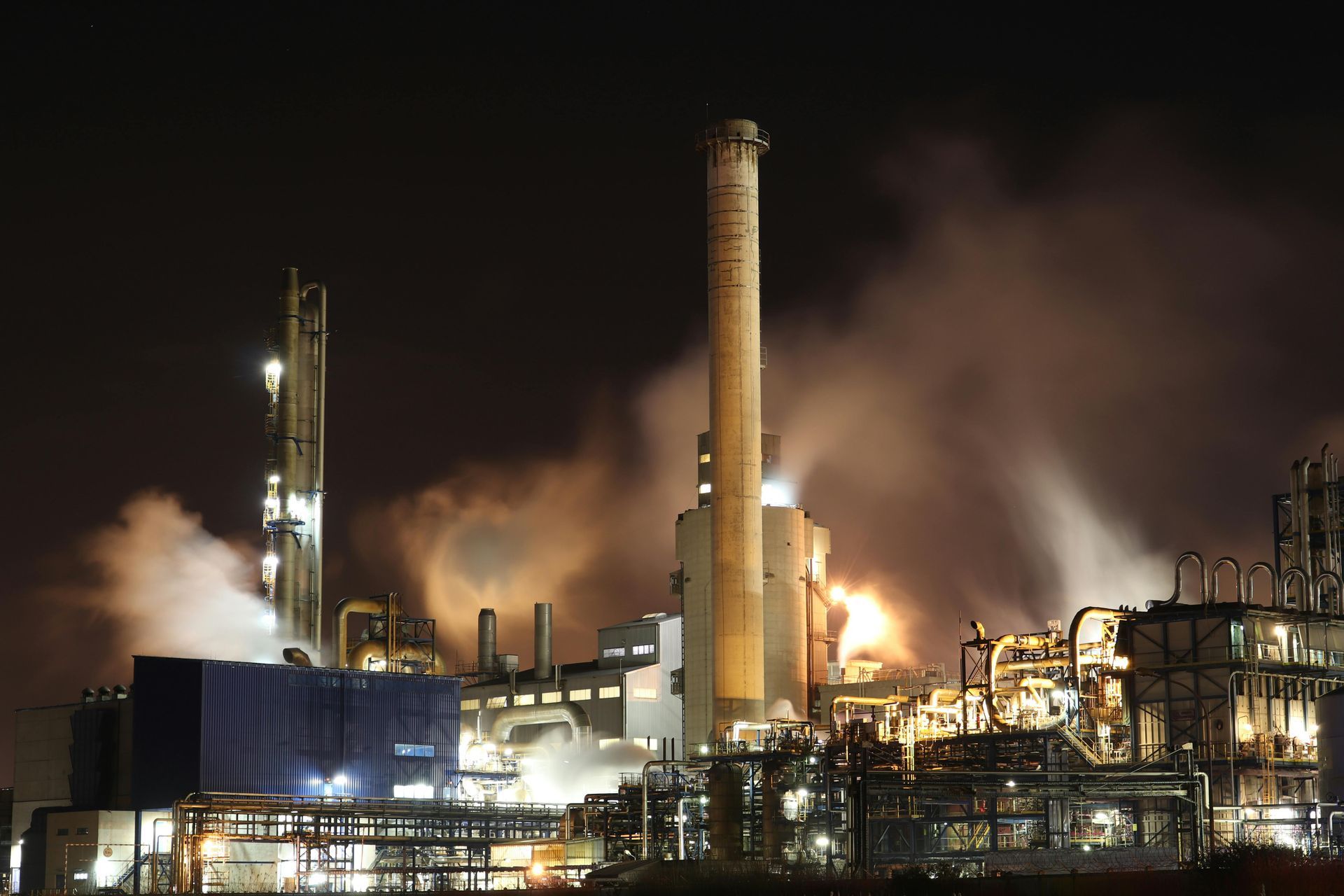 A factory at night with smoke coming out of the chimneys