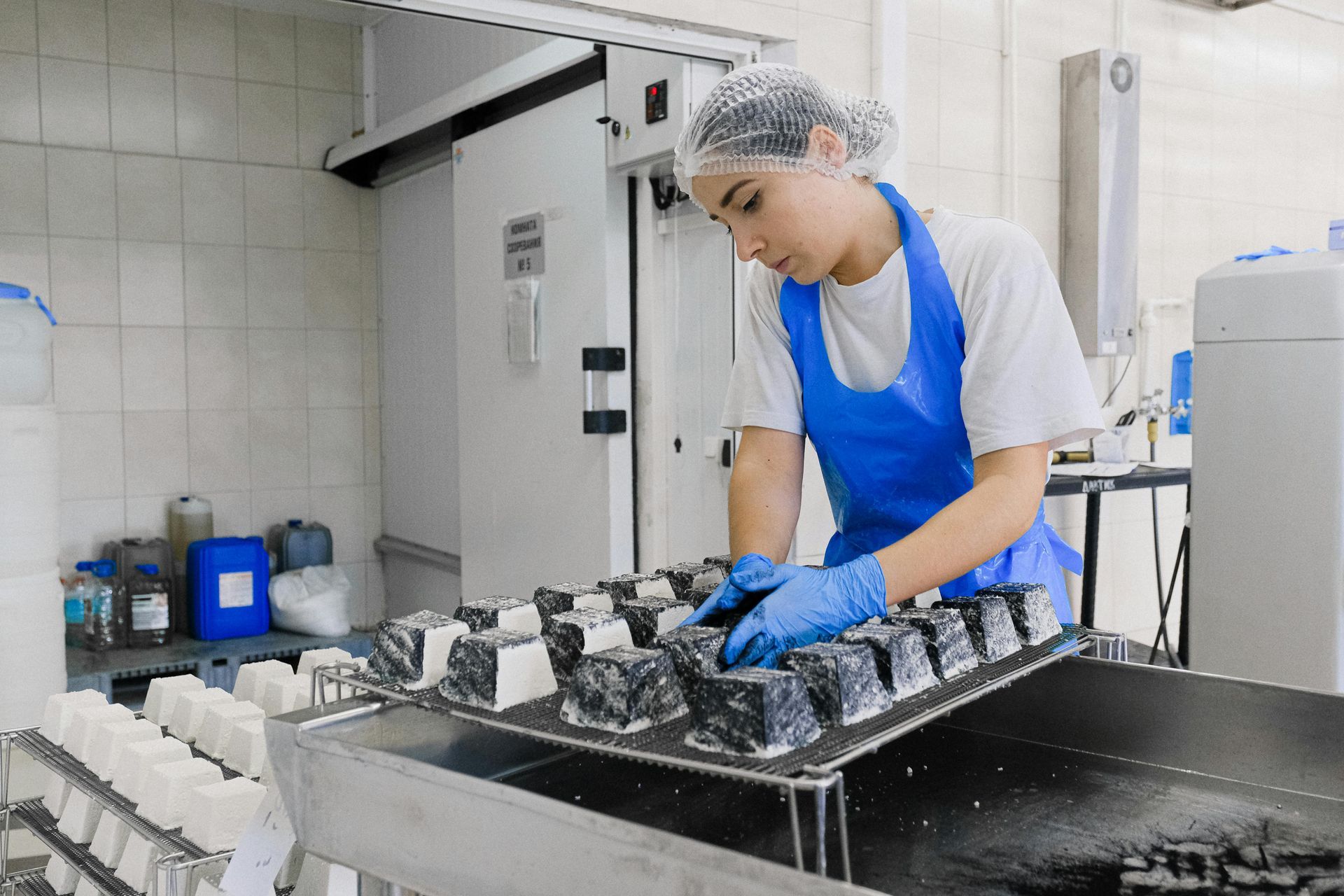 A woman in a blue apron is working in a kitchen.