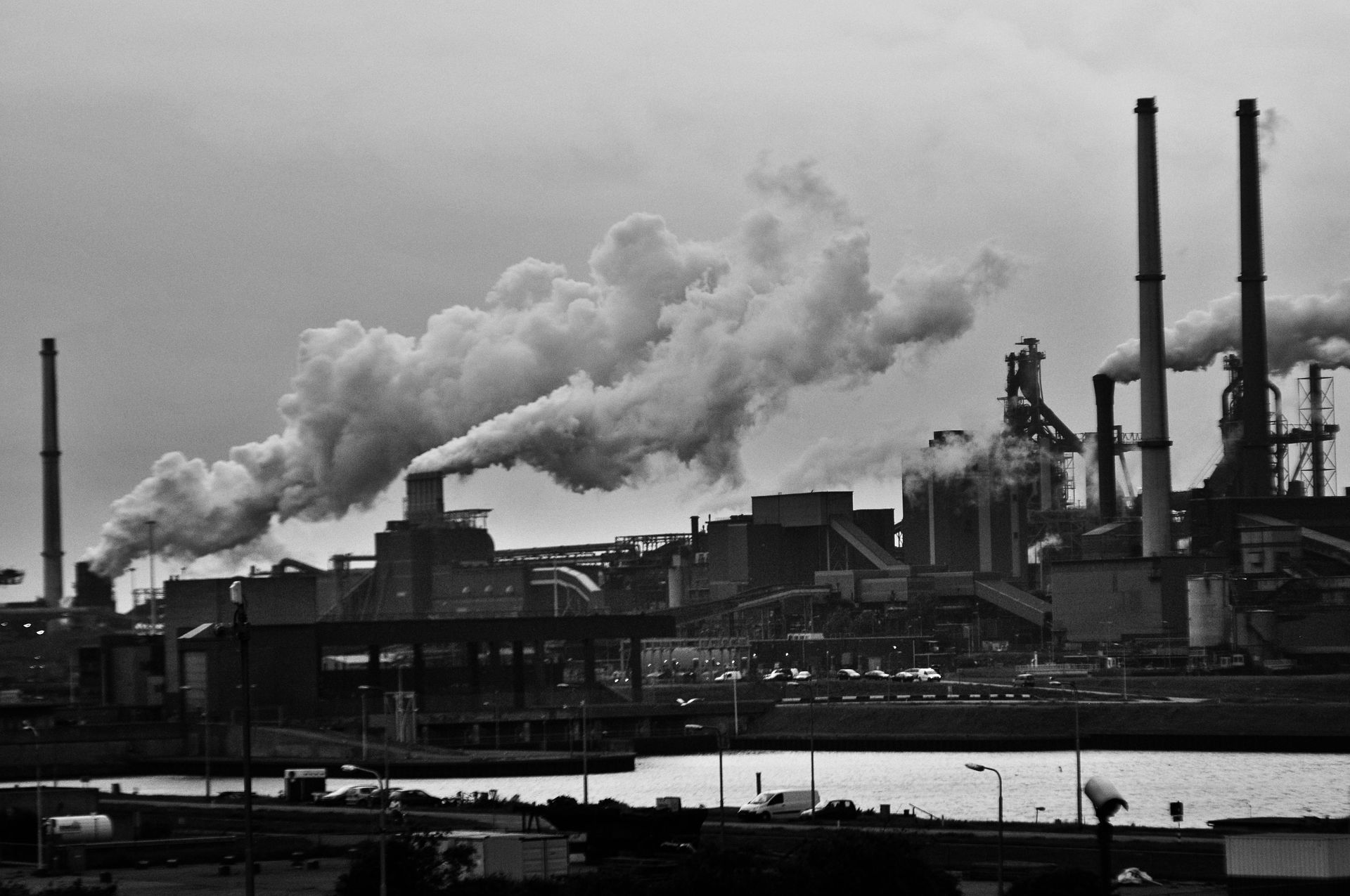 A black and white photo of a factory with smoke coming out of the chimneys.