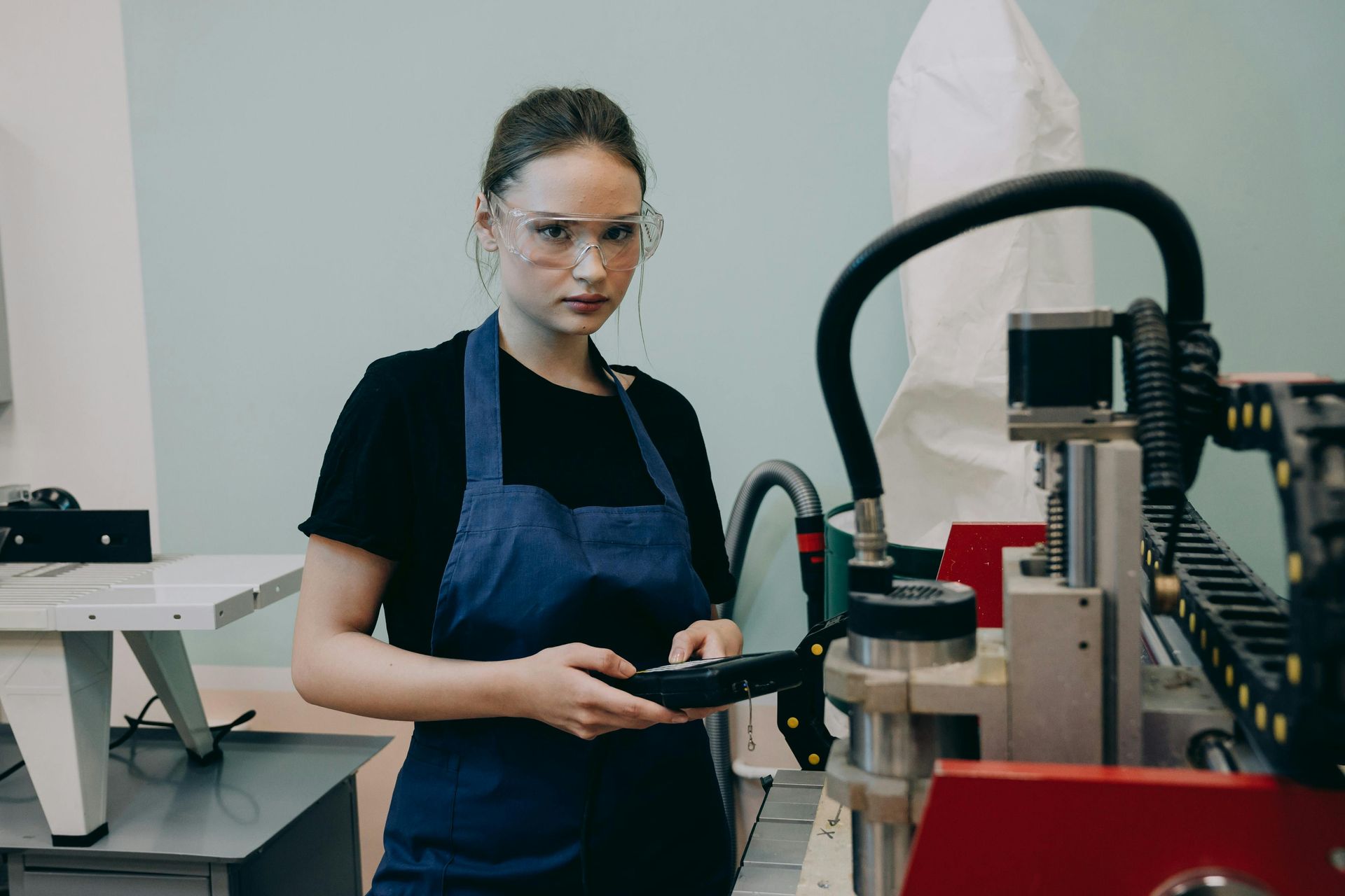 A woman is standing in front of a machine holding a tablet.