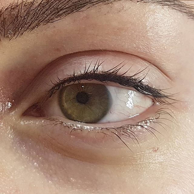 Eine Nahaufnahme des grünen Auges einer Frau mit langen Wimpern.