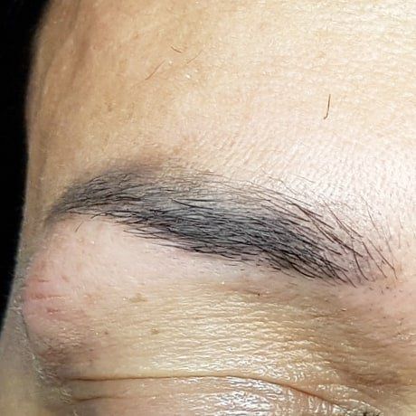 Eine Nahaufnahme der Augenbrauen einer Frau mit einer schwarzen Augenbraue.