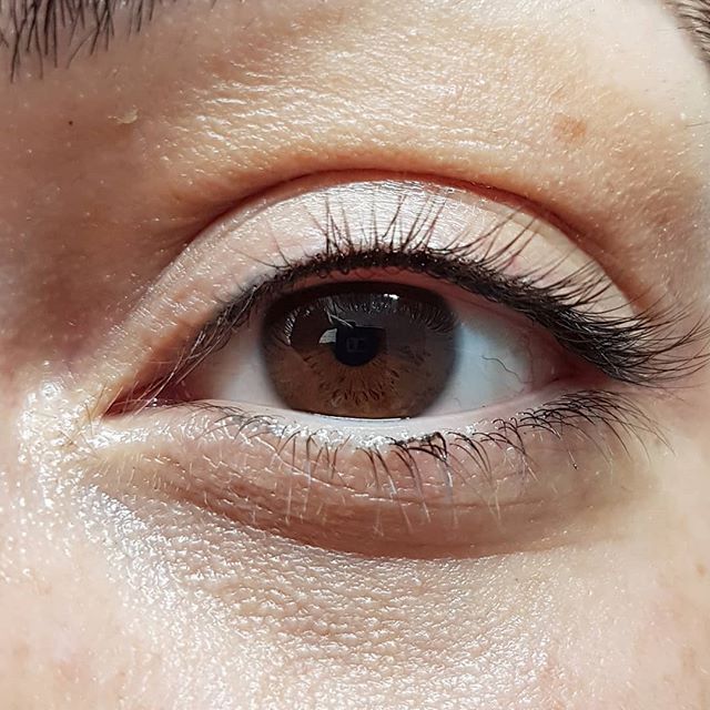 Eine Nahaufnahme des braunen Auges einer Frau mit langen Wimpern