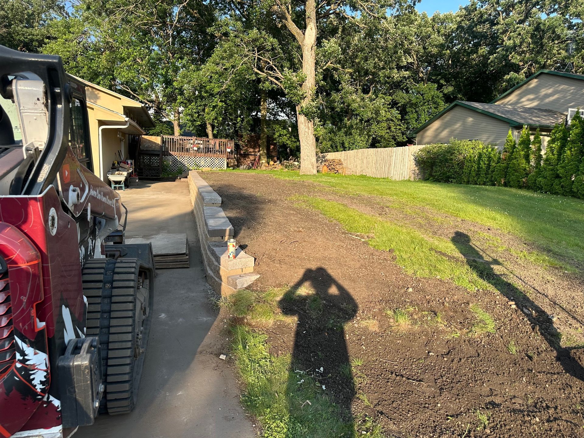A shadow of a person is cast on the ground next to a tractor. A shadow of a person is cast on the ground next to a tractor.