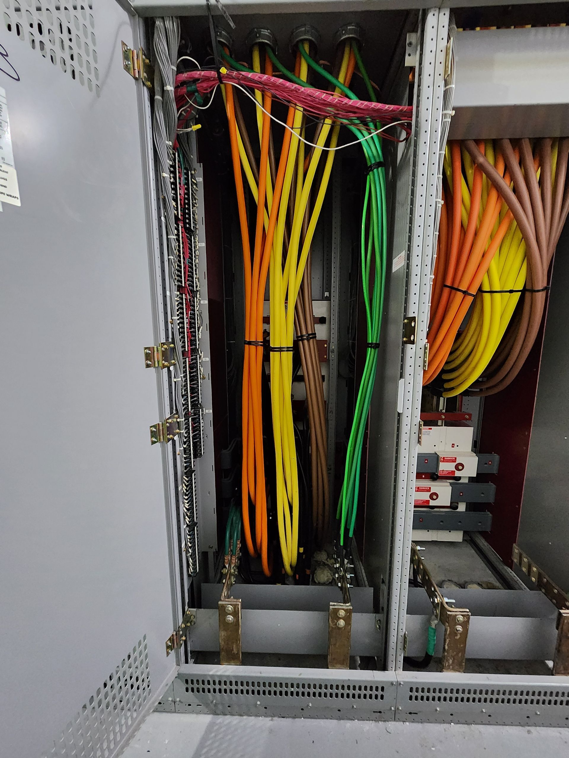 Electrical cabinet with bundles of colored wires secured inside.