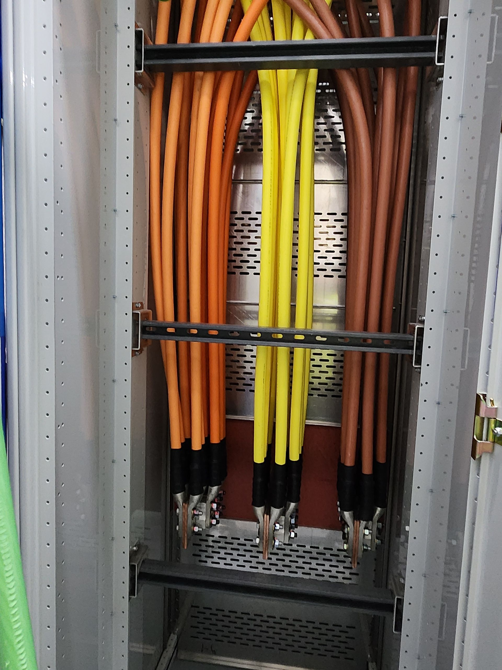 Orange, yellow, and brown electrical cables bundled in a metal cabinet.