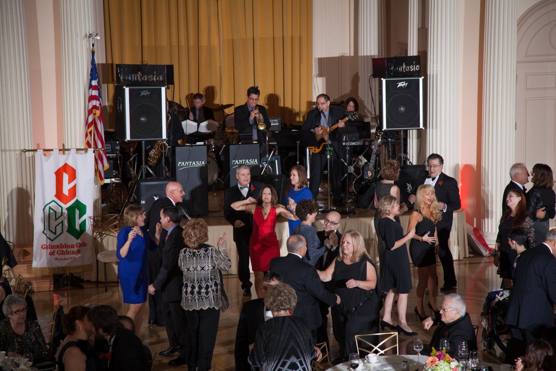 A group of people are dancing on a dance floor in front of a band.