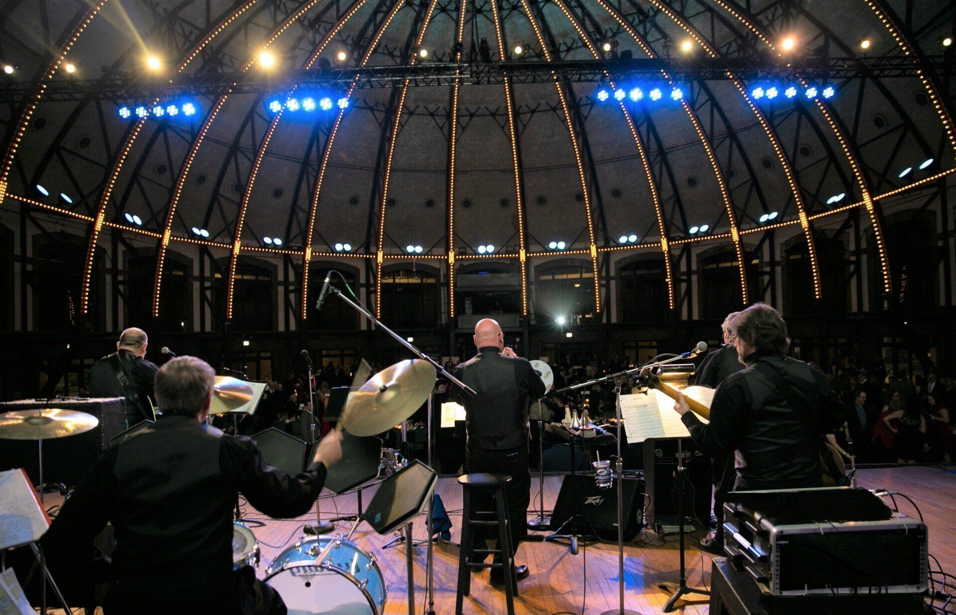 A group of men are playing drums on a stage in front of a crowd.
