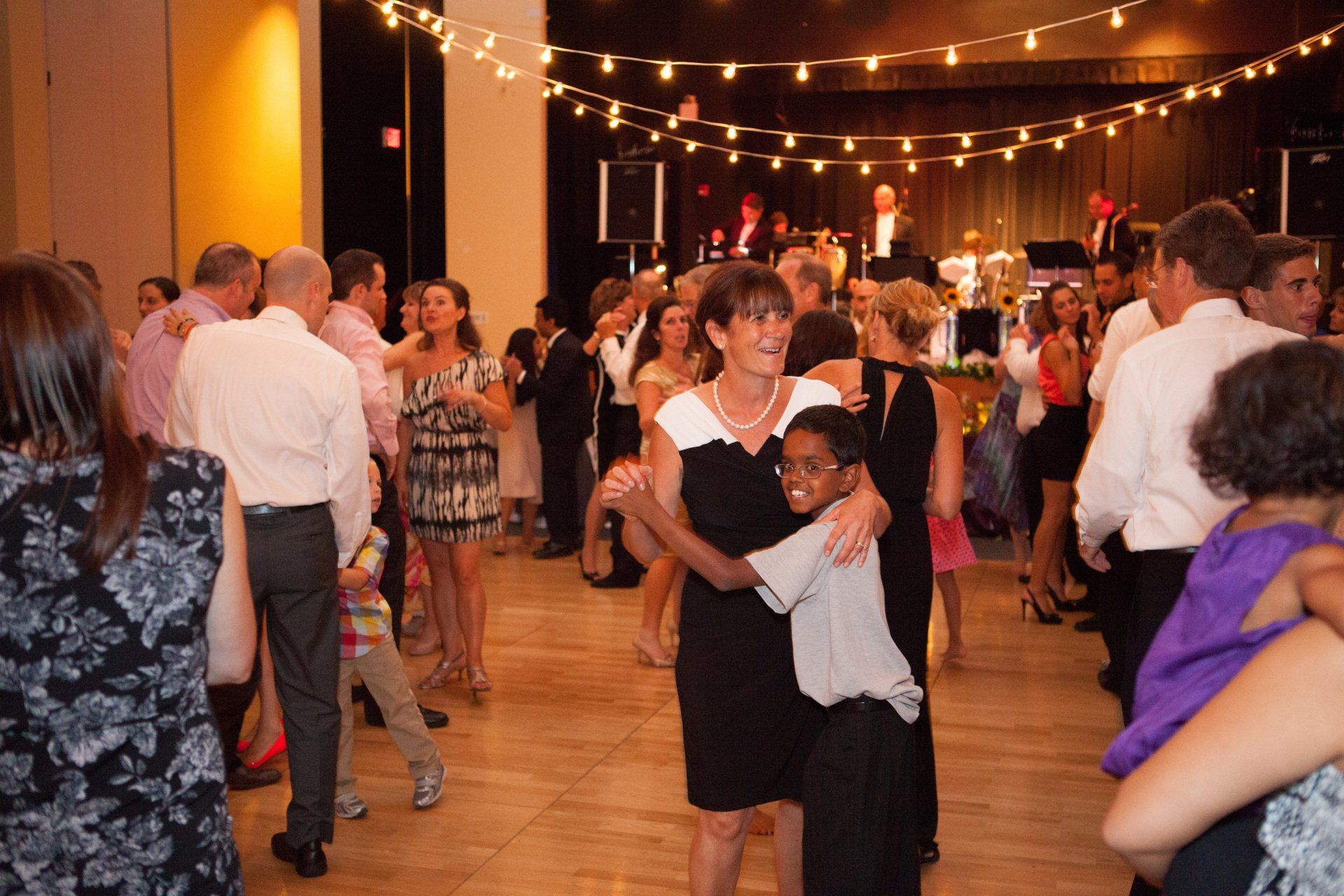 A group of people are dancing in a room with string lights