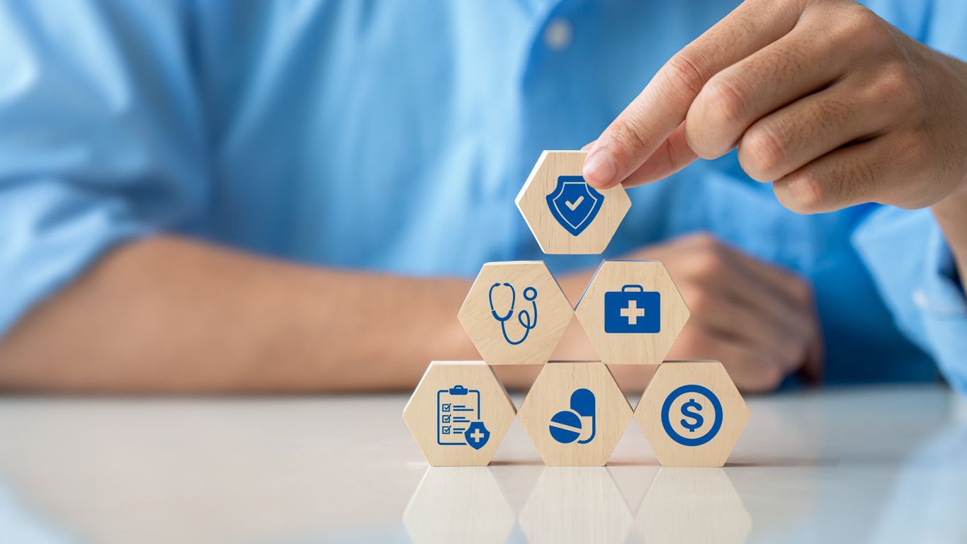 Person building healthcare insurance blocks with protection symbol on top.
