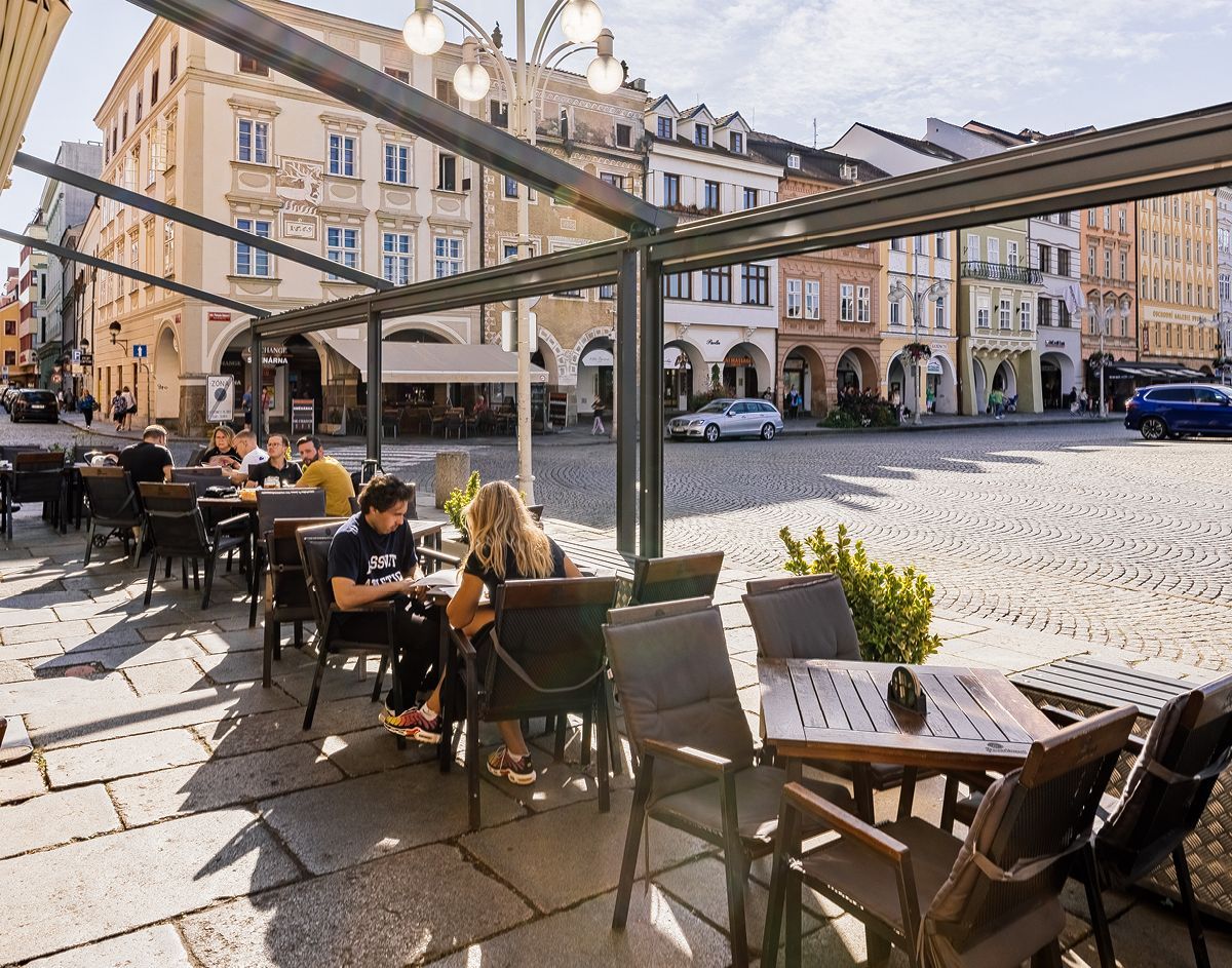 Skupina lidí sedí u stolů mimo restauraci.
