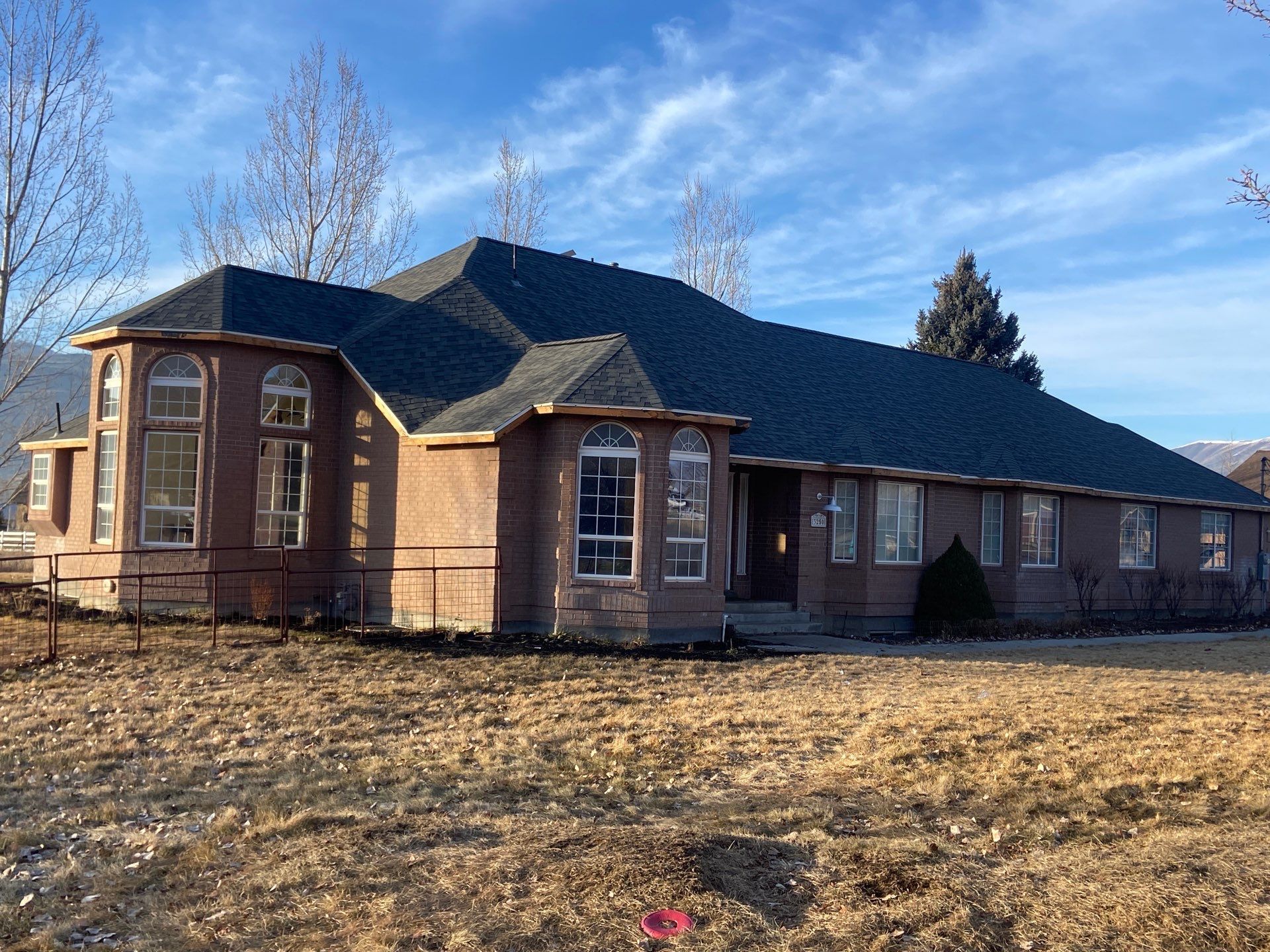 House with dark roof and tan stucco exterior, with multiple windows.