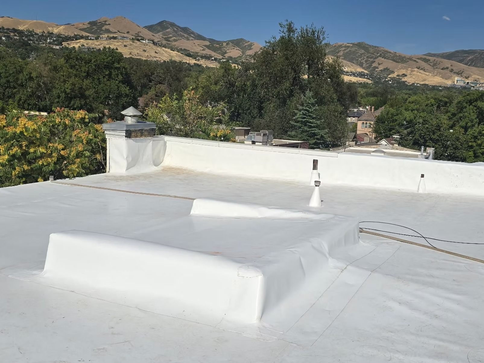 White flat roof with vents and a mountain backdrop.